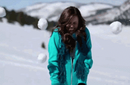gif of a person smiling with snowballs are thrown at them