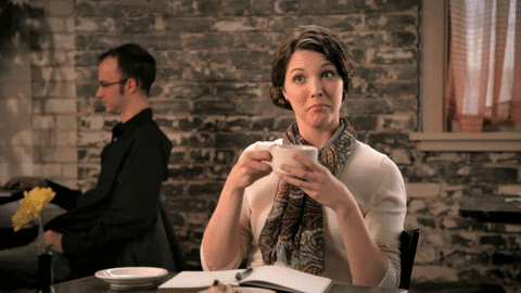 gif a woman holding a mug of coffee up in a toast